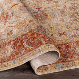 Close-up of the Kilsby Area Rug showing its traditional pattern, warm rust, gold, and beige tones, and soft texture. Fold