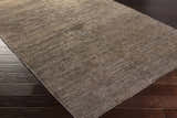Close-up of the hand-woven Kingwood Area Rug. Dark and light brown viscose rug with subtle texture on dark wood flooring. Corner