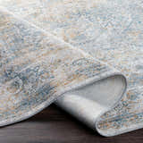 Close-up of Kintbury Area Rug showing blue, mustard, and off-white distressed pattern and texture. Machine woven polyester rug. Fold