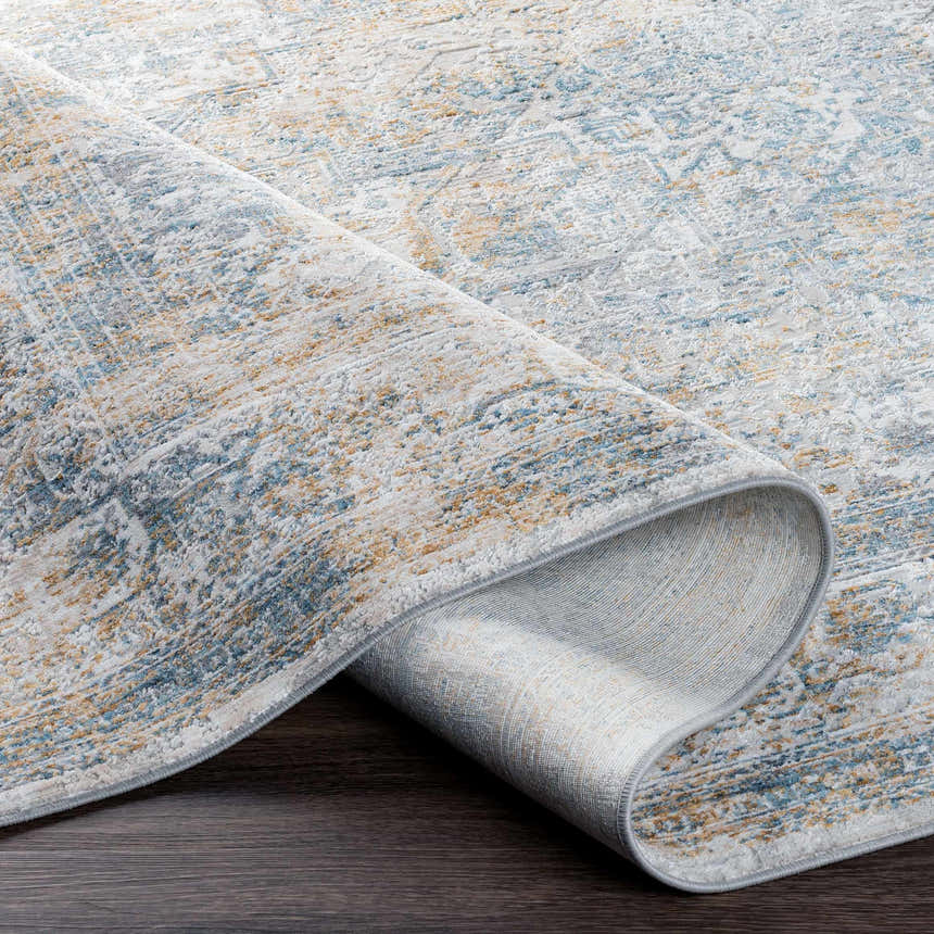 Close-up of Kintbury Area Rug showing blue, mustard, and off-white distressed pattern and texture. Machine woven polyester rug. Fold
