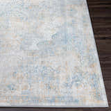Close-up of the Kintbury Area Rug. Bohemian style rug with blue, mustard, and off-white hues on a dark wood floor. Front