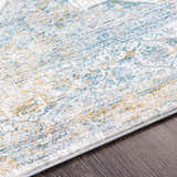Close-up of the Kintbury Area Rug. Features a blue, mustard, and off-white bohemian pattern with a machine-woven texture. Texture