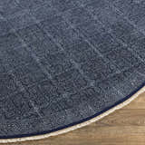 Close-up of the hand woven Kilburn Blue Cotton Round Carpet with a subtle pattern and fringe. Front