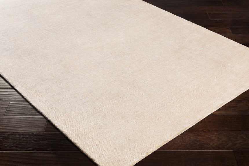 Close-up of the hand-loomed Klickitat Area Rug in peach and white, showing the subtle texture on dark wood floors. Corner