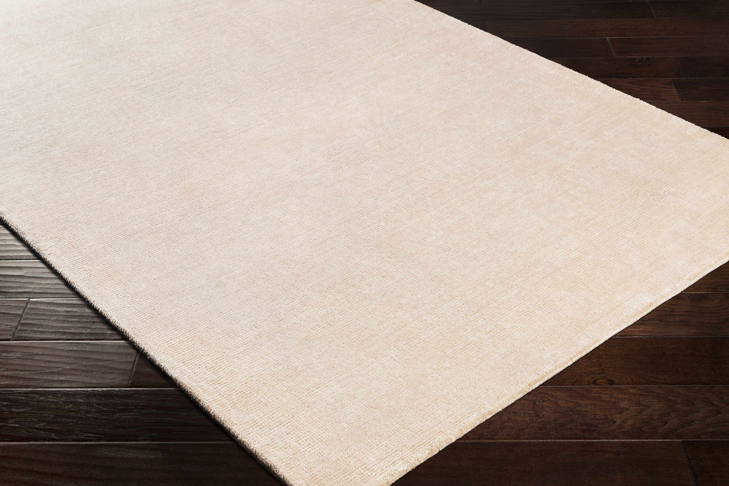 Close-up of the hand-loomed Klickitat Area Rug in peach and white, showing the subtle texture on dark wood floors. Corner