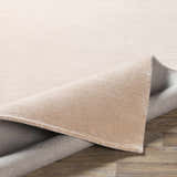 Close-up of the peach Klickitat Area Rug showing the hand-loomed texture and backing on a wood floor. Fold