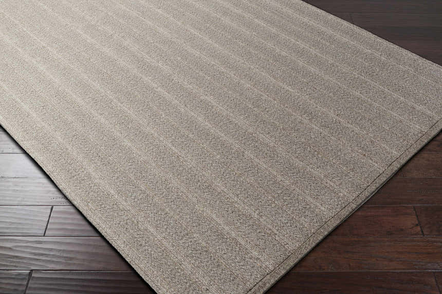 Close-up of the hand woven Kempston Gray rug showing its texture and subtle stripe pattern on dark wood floors. Corner