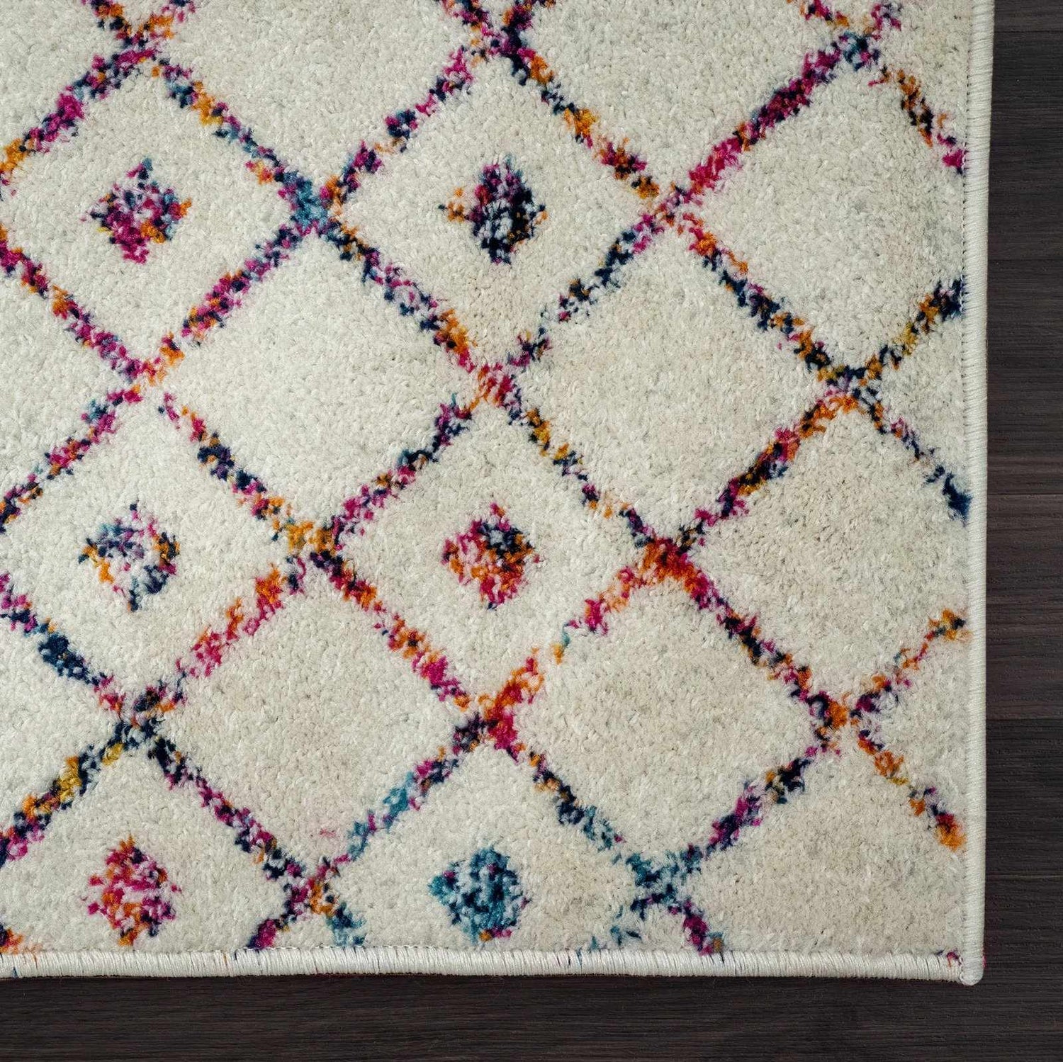 Close-up of the Marash KMRSH-4600 area rug. Off-white rug with colorful diamond pattern in blue, purple, red, and orange. Swatch