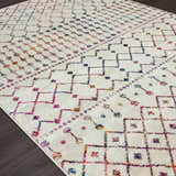 Close-up of the Marash KMRSH-4600 area rug. Off-white rug with colorful bohemian diamond and geometric patterns. Corner