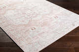 Close-up of the Kendal Area Rug showing a cream and pale pink traditional pattern on dark wood floors. Corner