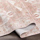 Close up of the Kendal Area Rug showing its light pink, cream, and beige traditional pattern and texture. Fold