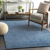Living room scene with a blue Kendall Carpet, wood chair, and glass console table. Roomscene-Rectangle
