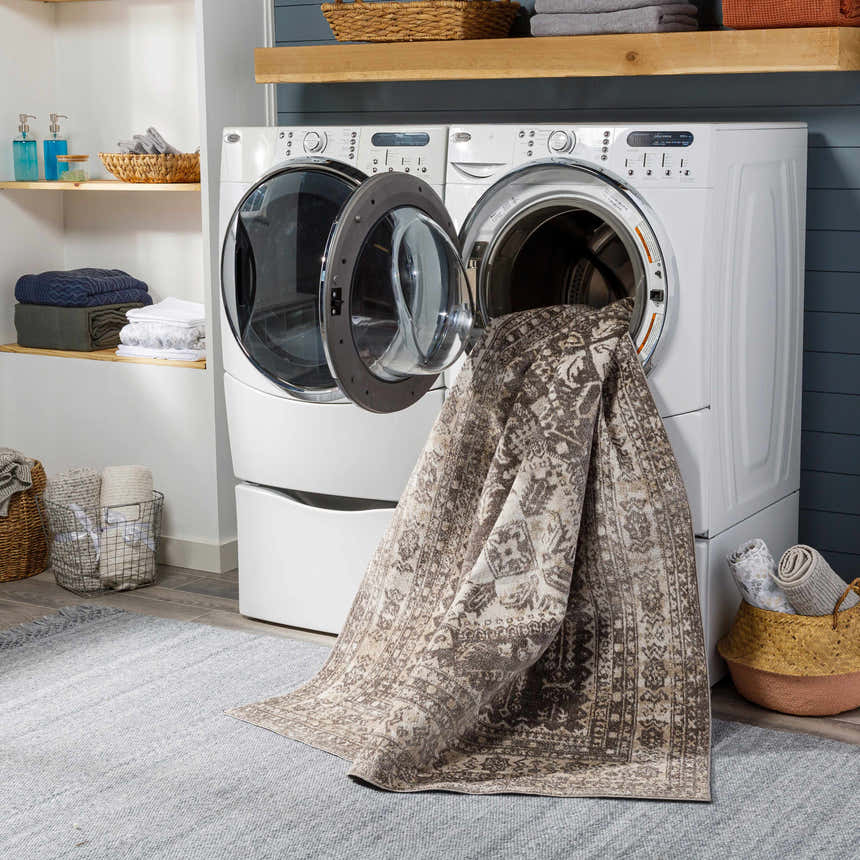 Laundry room scene with Kingscourt Washable Area Rug in the washing machine, showing its cream, brown, and oriental design. Washing-Machine