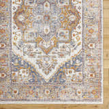 Close-up of Kokstad Area Rug. Traditional floral pattern in arctic stone, beige, brown, mocha, and taupe on wood floor. Corner