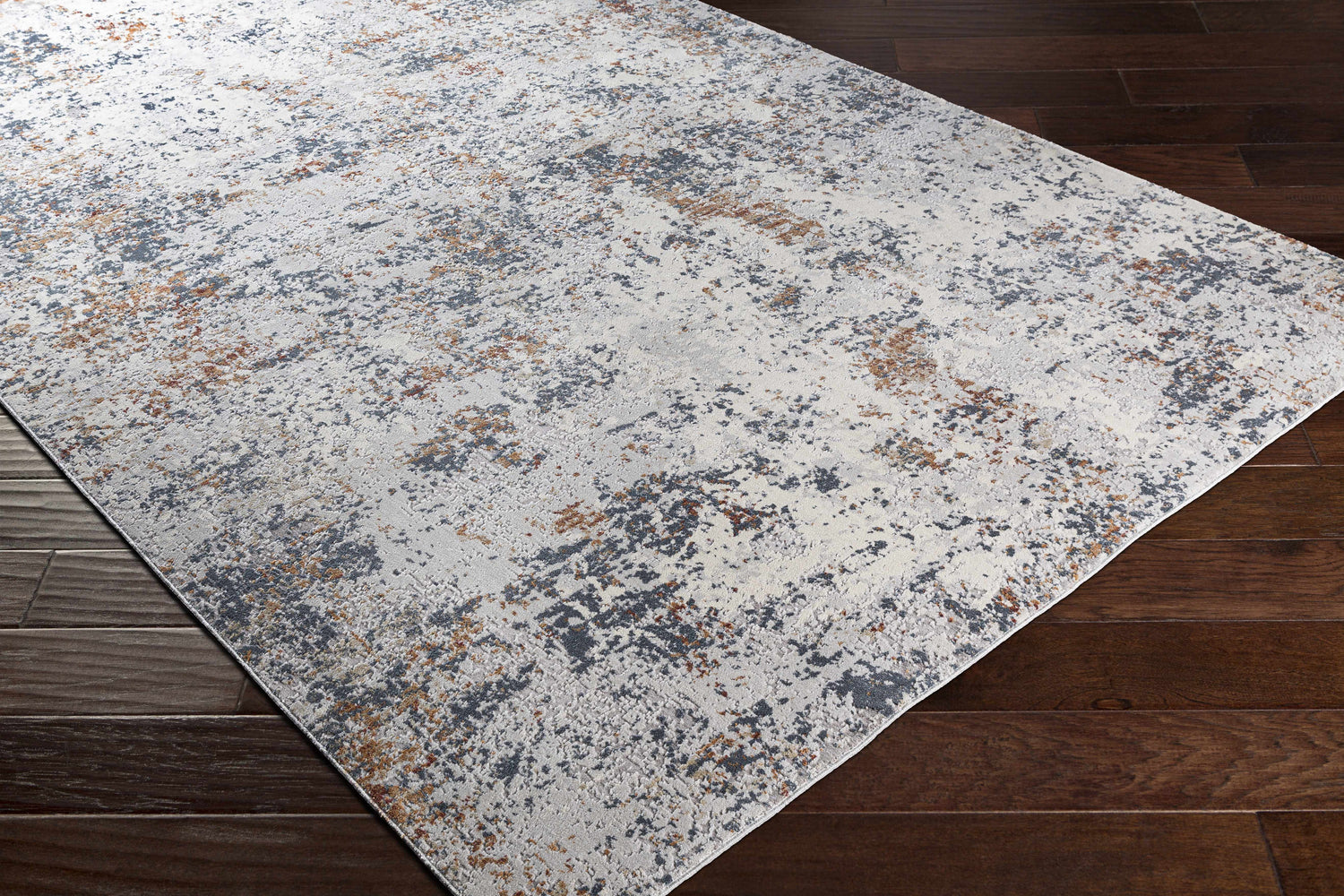 Close-up of Kearny Area Rug, a contemporary rug in brick red, brown, charcoal, and light gray on dark wood floors. Corner