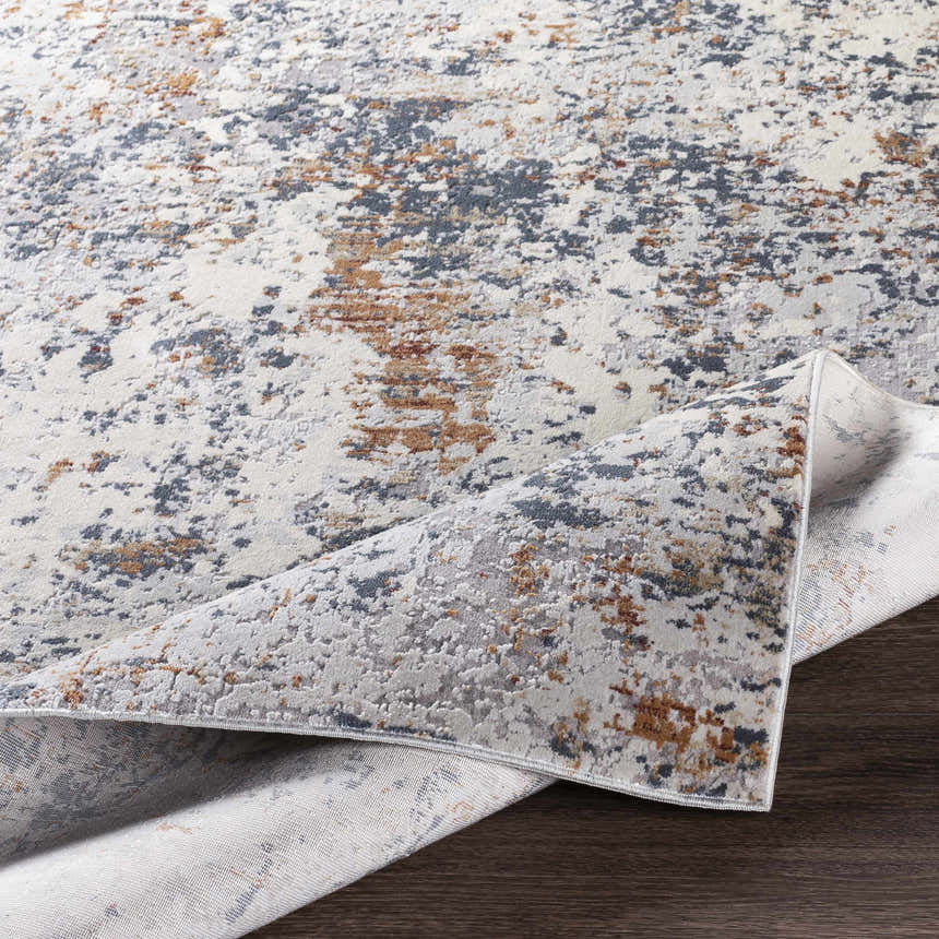 Close-up of the Kearny Area Rug, a contemporary design in brick red, brown, charcoal, beige, and gray. Machine-woven texture. Fold