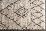 Close-up of the Kunia Area Rug. Shag rug with a charcoal geometric pattern on an ivory and light beige background. Corner