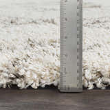 Close up of the Kunia Area Rug showing the shag texture and pile height with a ruler. Colors: ivory, taupe. Pile