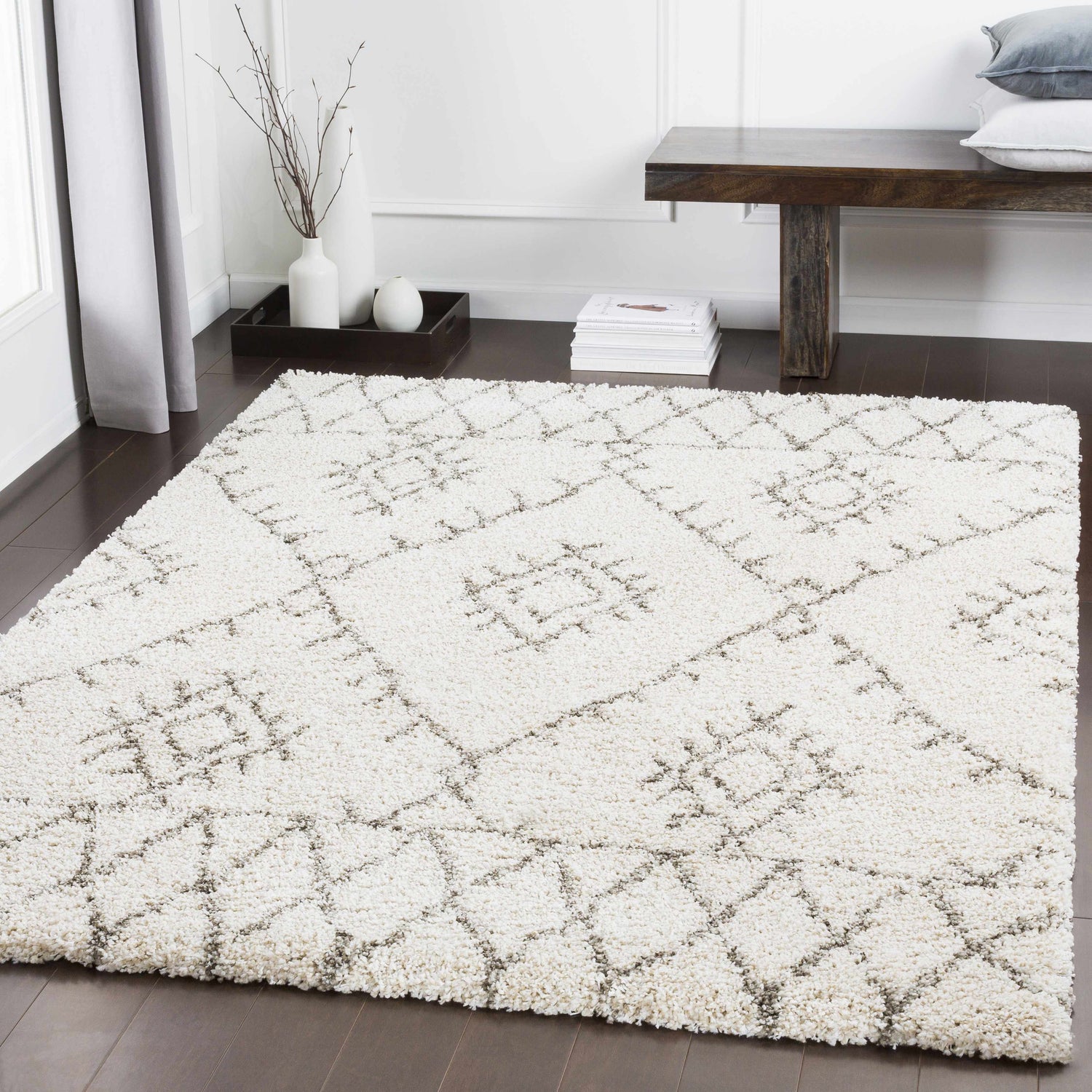 Living room scene with a Kunia Area Rug. The rug is ivory with a charcoal geometric pattern. Bench and decor complete the look. Roomscene-Rectangle