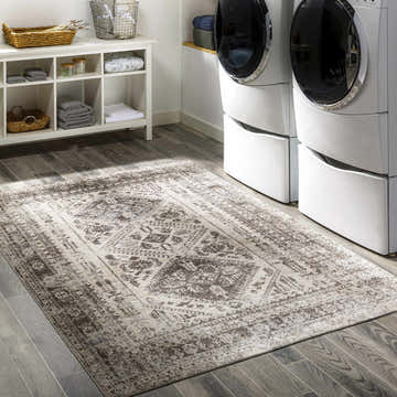 Laundry room with Ladybrand Washable Area Rug in brown, beige, and gray. White shelving and stacked washer/dryer. Roomscene-Rectangle