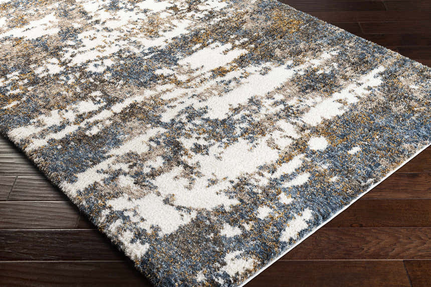 Close-up of the Lafontaine Boutique Area Rug. Cream, blue, brown, and mustard abstract pattern. Shag texture. Corner