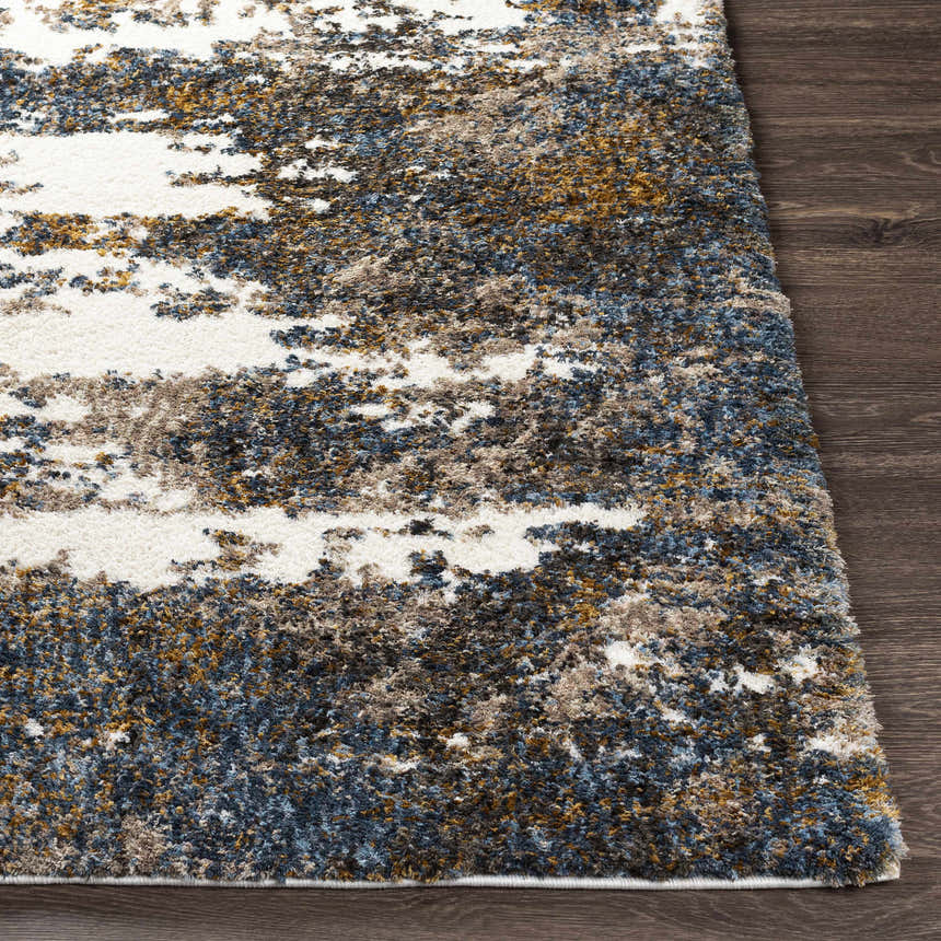 Close-up of the shag Lafontaine Boutique Area Rug. Cream, blue, brown, and mustard colors on a dark wood floor. Front
