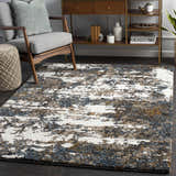 Living room scene with Lafontaine Boutique Area Rug. Cream, blue, brown, and mustard tones. Modern console table and gray armchair. Roomscene-Rectangle