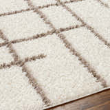 Close up of the Lale Area Rug showing its beige shag texture and dark brown geometric pattern. Texture