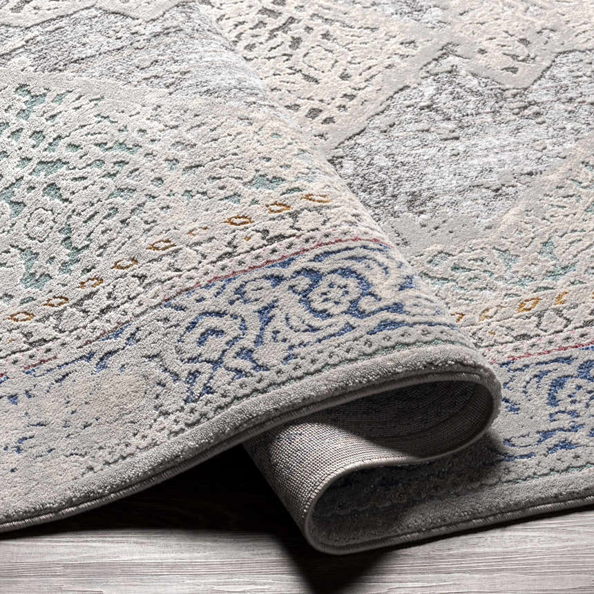 Close-up of the Laplace Area Rug showcasing its gray, blue, and mustard vintage-style pattern and soft texture. Fold