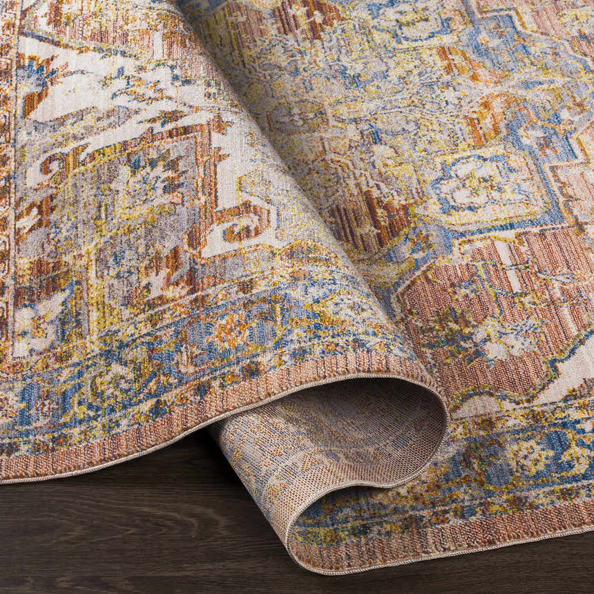Close-up of the Lappe Area Rug, showcasing its cream, blue, and rust bohemian pattern and machine-woven texture. Fold