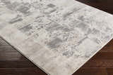 Close-up of the Lares Area Rug showcasing its charcoal, light beige, and gray contemporary pattern on dark wood floors. Corner