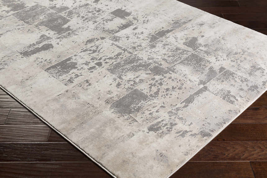 Close-up of the Lares Area Rug showcasing its charcoal, light beige, and gray contemporary pattern on dark wood floors. Corner
