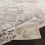 Close-up of the Lares Area Rug, showing its charcoal, light beige, and gray contemporary pattern and machine-woven texture. Fold