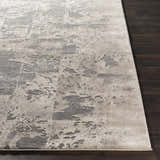 Close-up of the Lares Area Rug. Charcoal, light beige, medium gray and tan abstract pattern. Machine woven polypropylene rug. Front
