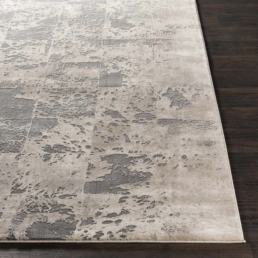 Close-up of the Lares Area Rug. Charcoal, light beige, medium gray and tan abstract pattern. Machine woven polypropylene rug. Front