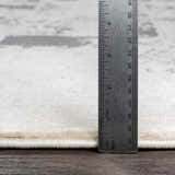 Close-up of Lares Area Rug pile height in light beige and gray with a ruler showing the thickness. Pile