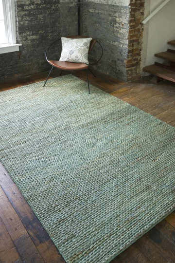 Farmhouse mudroom scene with dusty sage Latexo Jute Rug, wood floors, brick wall, and modern chair. Roomscene-Rectangle