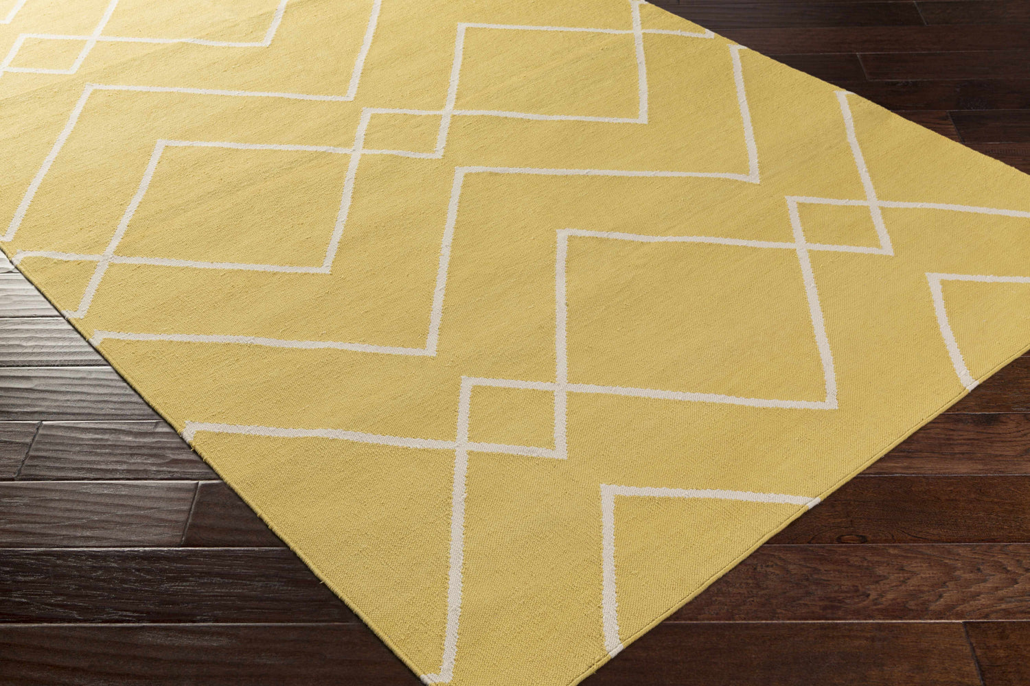 Close-up of the hand-woven Leatherwood Area Carpet. Off white geometric pattern on a tan, 100% cotton rug. Contemporary style. Corner