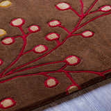 Close up of the Brown Elsu Area Rug showing the floral pattern with burgundy and tan accents on a brown wool rug. Texture