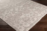 Close-up of the beige and charcoal Lerwick Carpet, a hand-knotted wool rug with a traditional floral pattern and fringe. Corner