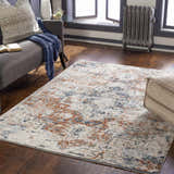 Living room scene with a brick red, cream, and denim Loughrea Area Rug, gray couch, and wood floors. Roomscene-Rectangle