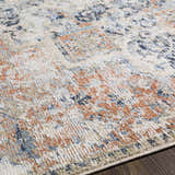 Close-up of the Loughrea Area Rug featuring brick red, cream, denim, and gray tones on a textured, machine-woven design. Texture