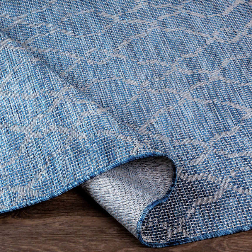 Close-up of Lidlington Flatweave Area Carpet in blue. Contemporary style with a subtle geometric pattern. Fold