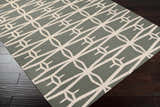 Close-up of the charcoal Lipan Area Rug. Contemporary geometric design in charcoal and peach on dark wood floor. Corner