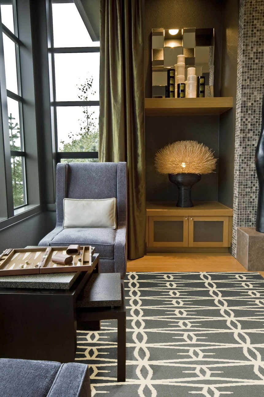 Living room scene with a charcoal and peach Lipan Area Rug, gray armchair, and dark wood furniture. Roomscene-Rectangle