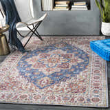 Living room scene with a Kapaa Blue Medallion Rug, white chair, blue throw, gold side table, and blue floor cushion. Roomscene-Rectangle
