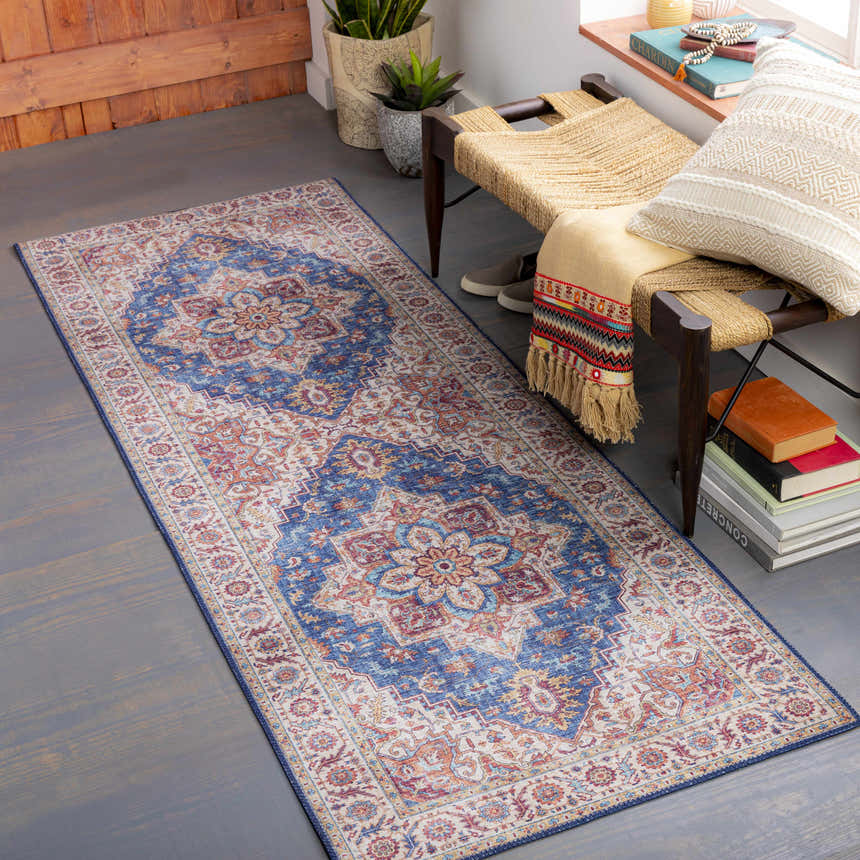 Entryway scene with a Kapaa Blue Medallion Rug, woven bench, books, and plants. Farmhouse style with beige, blue, and orange tones. Roomscene-Runner
