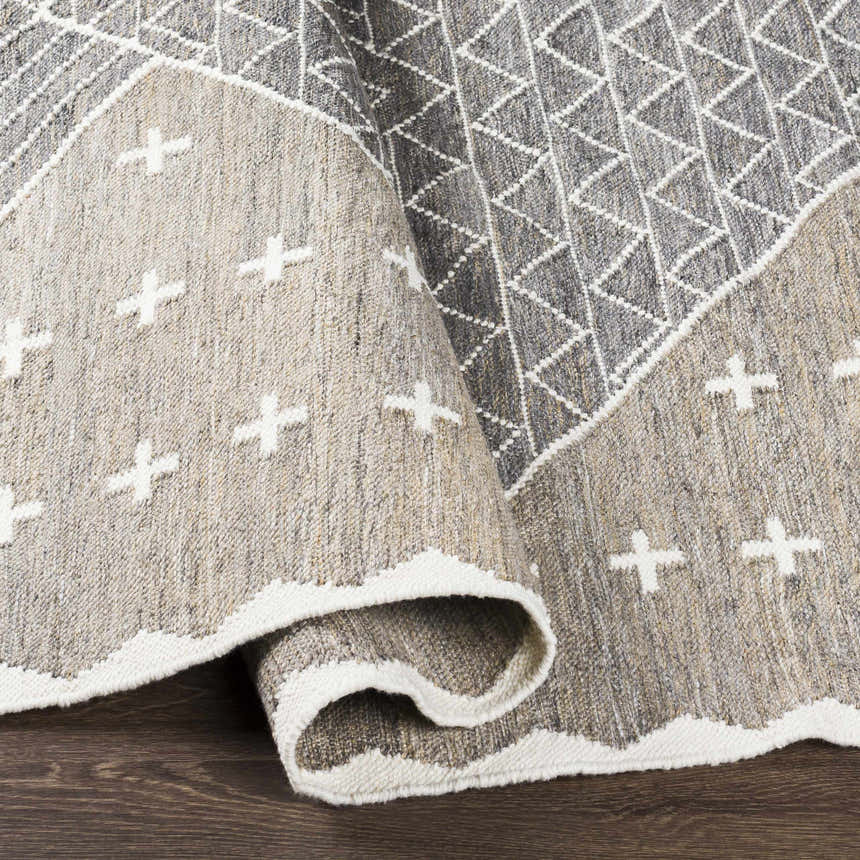 Close-up of Lodwar Area Rug showing charcoal, cream, and gray colors with a geometric and plus sign pattern. Hand woven texture. Fold