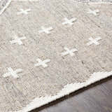 Close-up of the Lodwar Area Rug. Hand-woven rug in charcoal, cream, and gray with a geometric plus sign pattern. Texture