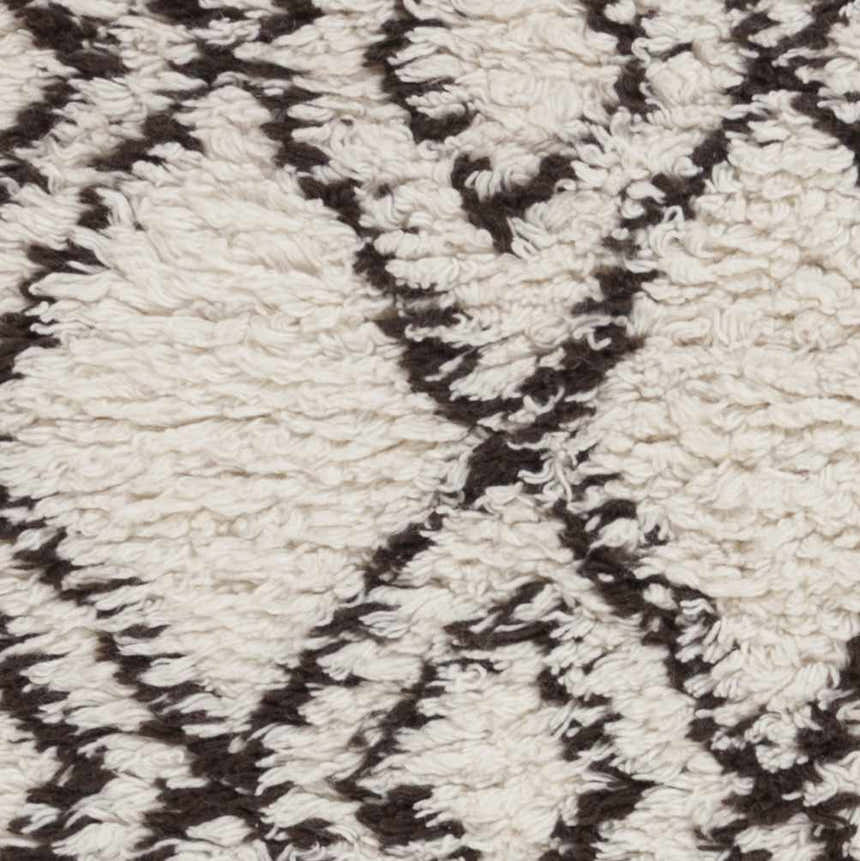 Close-up of the Lothian Area Rug showing charcoal diamond pattern on ivory wool shag texture. Swatch